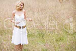 Woman standing outdoors holding grass smiling