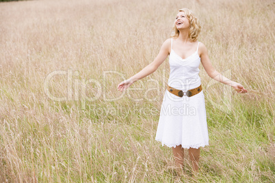 Woman standing outdoors holding grass smiling