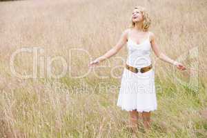 Woman standing outdoors holding grass smiling