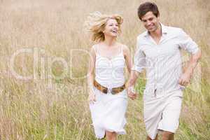 Couple running outdoors holding hands smiling
