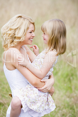 Mother holding daughter outdoors smiling