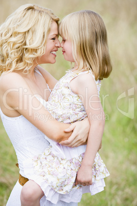 Mother holding daughter outdoors smiling