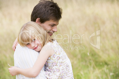 Father holding daughter outdoors smiling