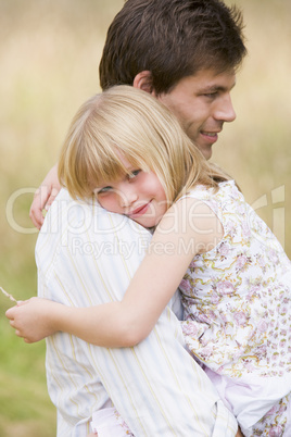 Father holding daughter outdoors smiling