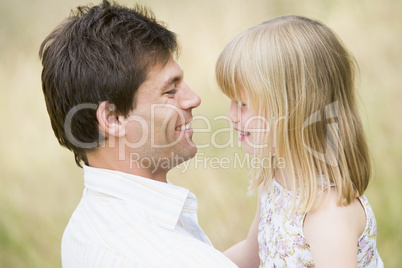 Father holding daughter outdoors smiling