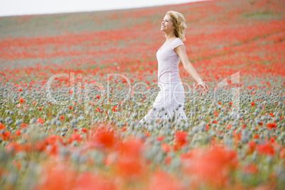 Woman walking in poppy field smiling
