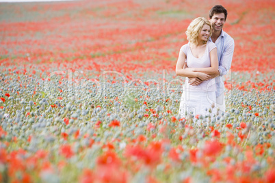 Couple in poppy field embracing and smiling