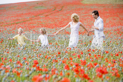 Family walking in poppy field holding hands smiling