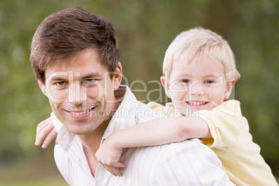 Father holding son outdoors smiling