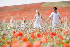 Family walking in poppy field holding hands smiling