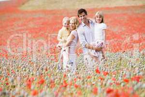 Family standing in poppy field smiling