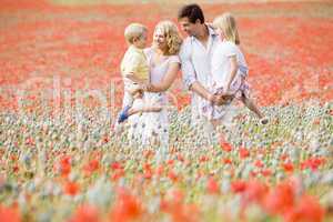 Family standing in poppy field smiling