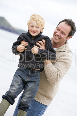 Father holding son at beach smiling