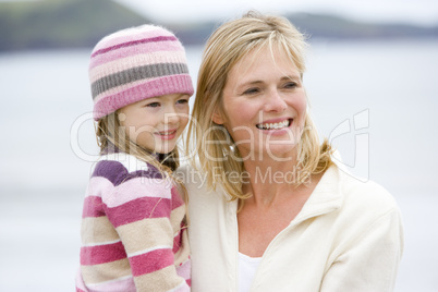 Mother holding daughter at beach smiling