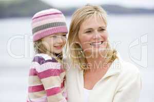 Mother holding daughter at beach smiling