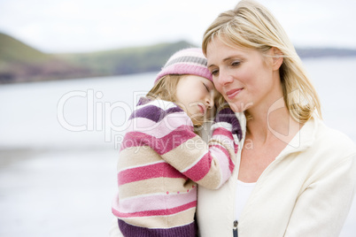 Mother holding sleeping daughter at beach