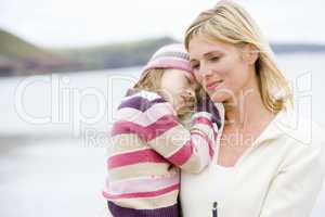 Mother holding sleeping daughter at beach