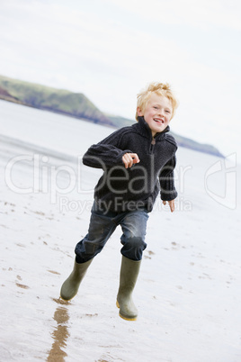 Young boy running on beach smiling