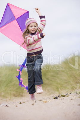 Young girl on beach with kite smiling