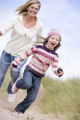 Mother and daughter running on beach smiling