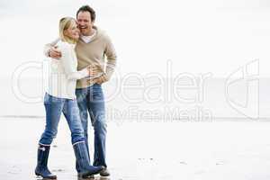 Couple walking on beach arm in arm smiling