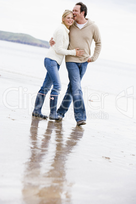 Couple walking on beach arm in arm smiling