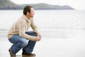 Man crouching on beach