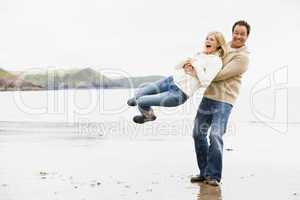 Couple playing on beach smiling