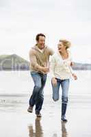 Couple running on beach smiling