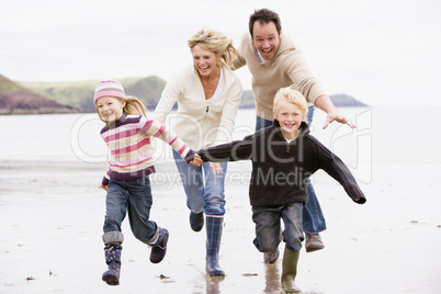 Family running on beach holding hands smiling