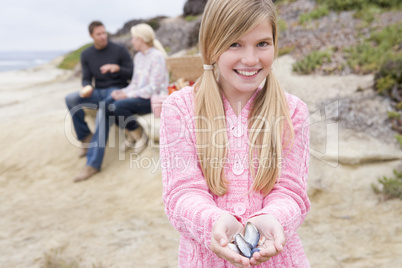 Family at beach with picnic smiling focus on girl with seashells