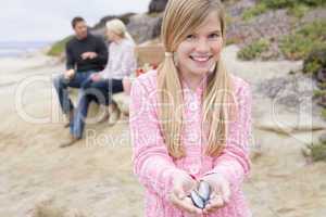 Family at beach with picnic smiling focus on girl with seashells