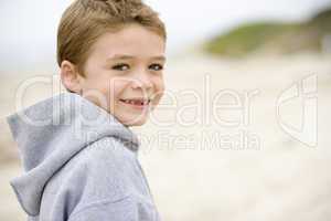 Young boy standing on beach smiling