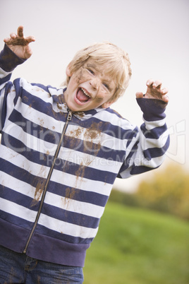 Young boy standing outdoors dirty and smiling