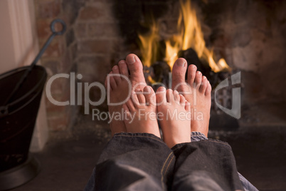 Father and son's Feet warming at a fireplace