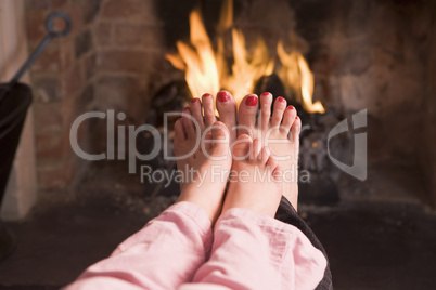 Mother and daughter's feet warming at a fireplace