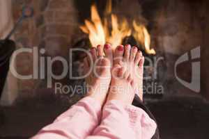 Mother and daughter's feet warming at a fireplace