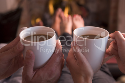 Feet warming at fireplace with hands holding coffee