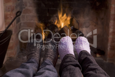 Couple's feet warming at a fireplace