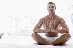 Man sitting on bed meditating