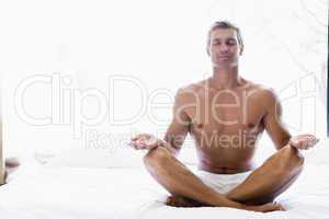 Man sitting on bed doing yoga