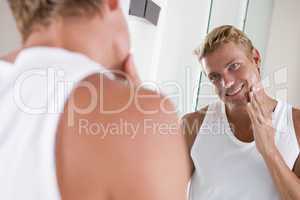 Man in bathroom applying face cream smiling