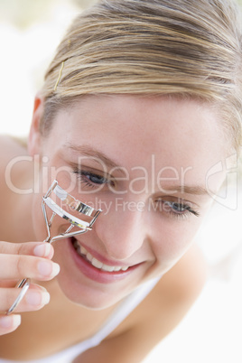 Woman with eyelash curler smiling
