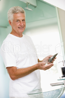 Man in bathroom applying aftershave and smiling