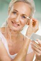 Woman applying eye makeup and smiling