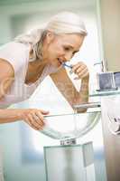 Woman in bathroom brushing teeth