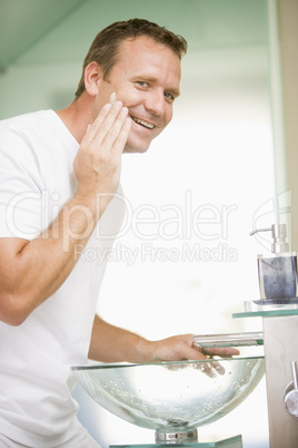 Man in bathroom applying shaving cream and smiling
