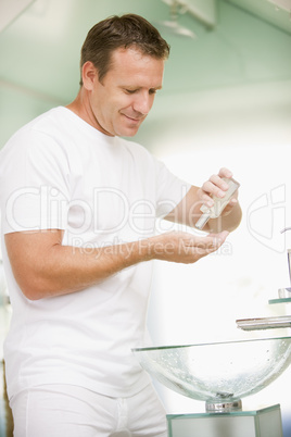 Man in bathroom applying aftershave and smiling