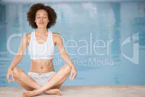 Woman sitting poolside doing yoga