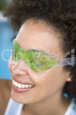 Woman sitting poolside using eye mask smiling